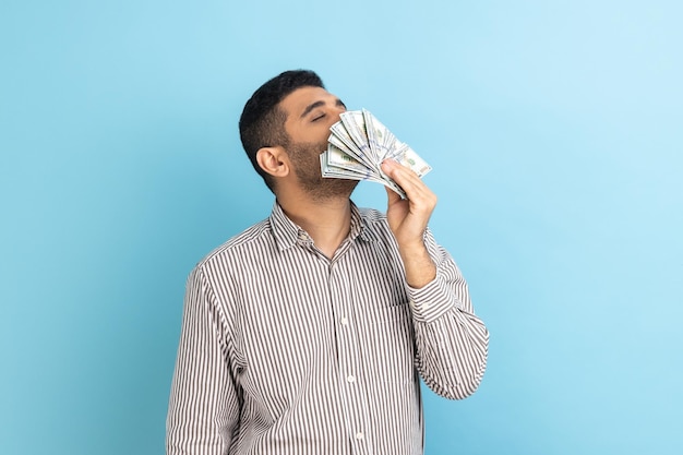 Un hombre de negocios arrogante y codicioso con barba que huele a billetes de dólar con expresión de placer