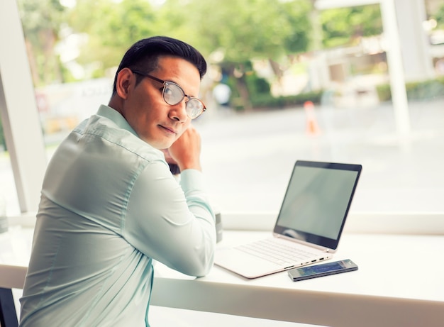 Hombre de negocios de Asia que trabaja con la computadora portátil mientras que se sienta la cafetería. Concepto de jóvenes empresarios