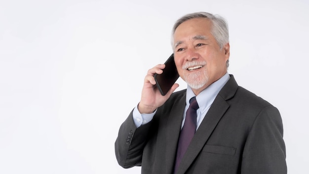 Un hombre de negocios asiático de alto nivel que usa un teléfono inteligente sonriendo se siente feliz aislado en un concepto de fondo blanco para el éxito empresarial de alto nivel