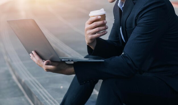 Hombre de negocios asiático y mujer hermosa joven que trabajan en una tableta digital de pie fuera del edificio de oficinas