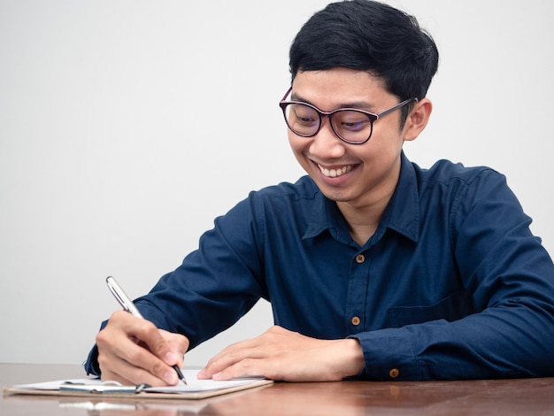 El hombre de negocios asiático que escribe en un documento en el escritorio se siente feliz con su trabajo