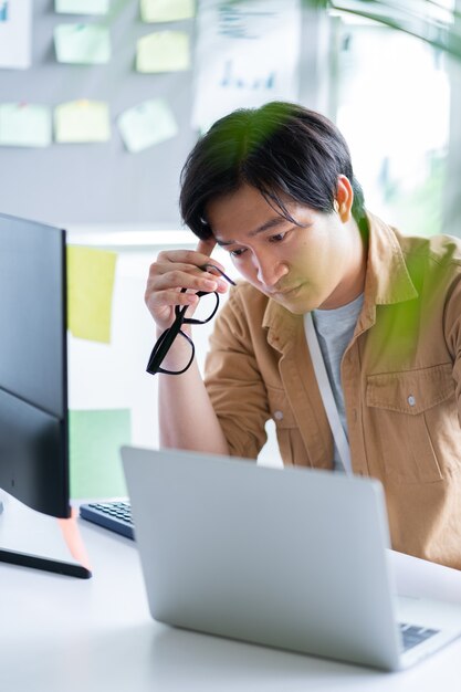 Hombre de negocios asiático que trabaja con la computadora en la oficina