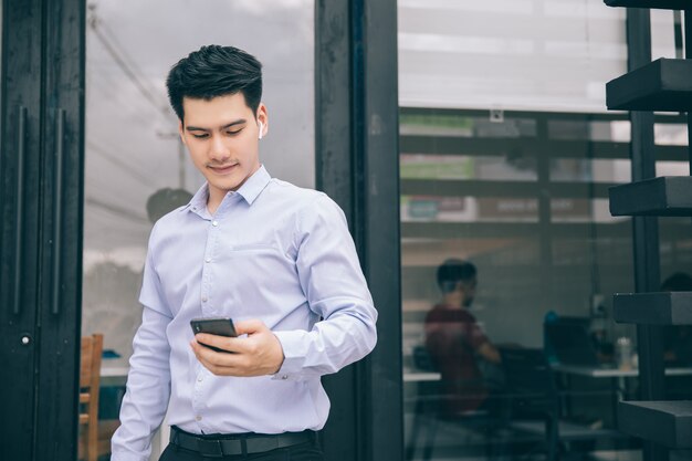 Hombre de negocios asiático sonriente feliz al aire libre con el teléfono elegante