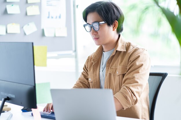 Hombre de negocios asiático trabajando con un portátil en la oficina