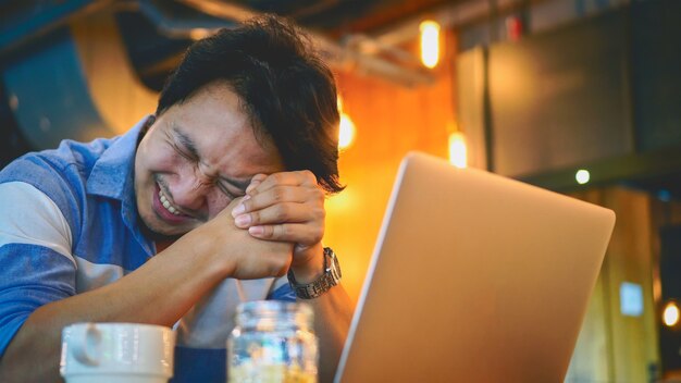 Hombre de negocios asiático en traje casual trabajando con la computadora en emoción de estrés en el spa de trabajo conjunto