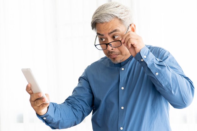 Hombre de negocios asiáticos viejo con cabello gris con gafas y trabajando en oficina