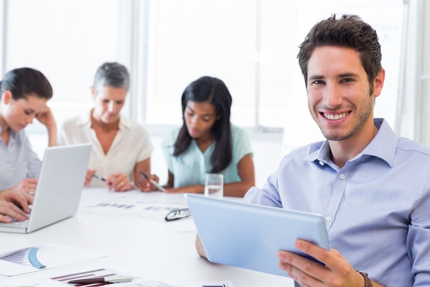 Hombre de negocios atractivo usando una tableta en el trabajo