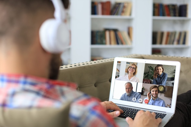 Hombre de negocios en auriculares acostado en el sofá hablar hablar en videollamada con colegas en la sesión informativa en línea