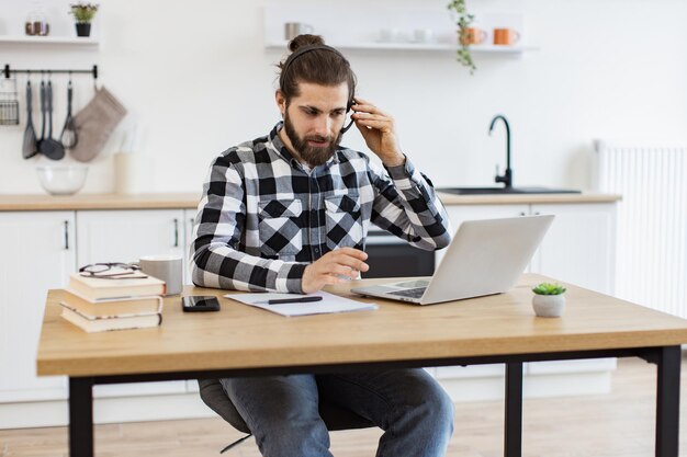 Hombre de negocios con auriculares gestando frente a la computadora mientras hace trabajo en casa