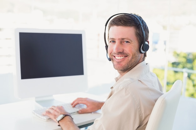 Hombre de negocios en auriculares sonriendo a la cámara