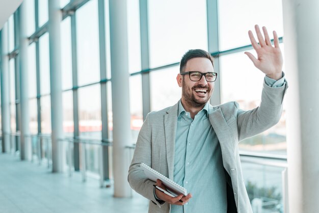 El hombre de negocios barbudo sonriente hermoso está agitando