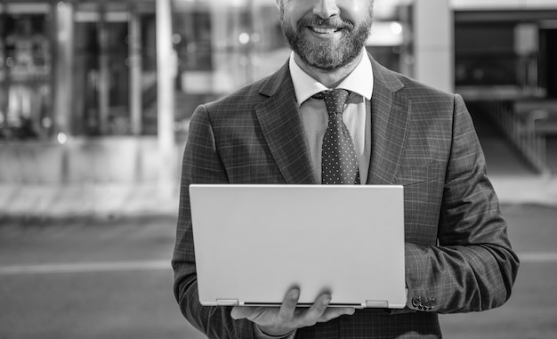 Hombre de negocios barbudo sonriente recortado en traje formal que trabaja en línea en redes informáticas