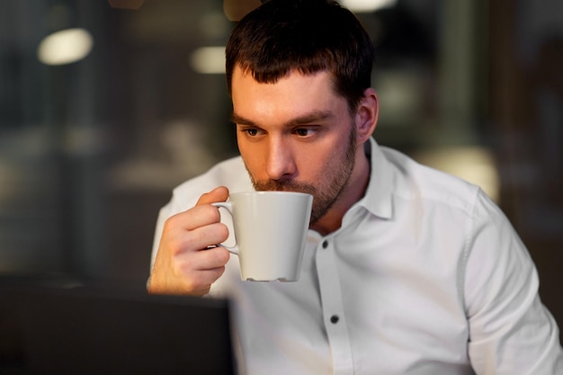 Un hombre de negocios bebiendo café en la oficina nocturna.