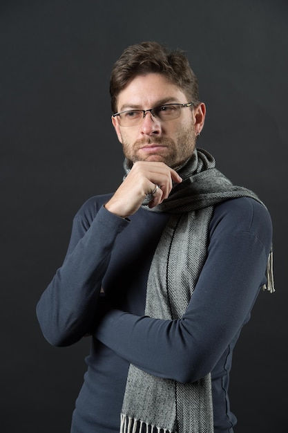 Hombre de negocios en bufanda y suéter. El hombre piensa en gafas en la cara barbuda. Moda, gafas, accesorios. Negocio, visión, concepto de solución. Corrección de la vista, cuidado de los ojos, salud,