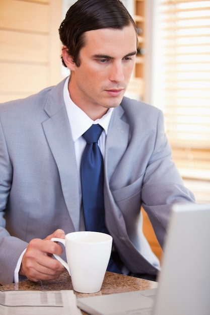 Hombre de negocios con café en su computadora portátil