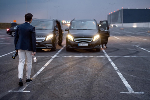 Hombre de negocios camina con bebidas alcohólicas a los coches al aire libre