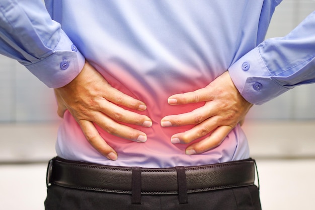 Hombre de negocios con camisa azul siente dolor de espalda Concepto médico y de salud