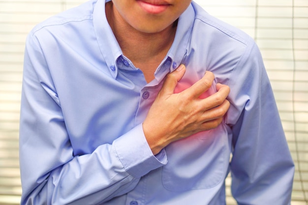 El hombre de negocios con camisa azul siente un dolor de pecho apretado en los síntomas izquierdos de la enfermedad cardíaca