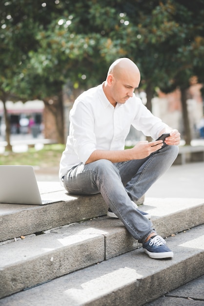 Foto hombre de negocios en camisa blanca que trabaja con la computadora portátil que se sienta en la escalera