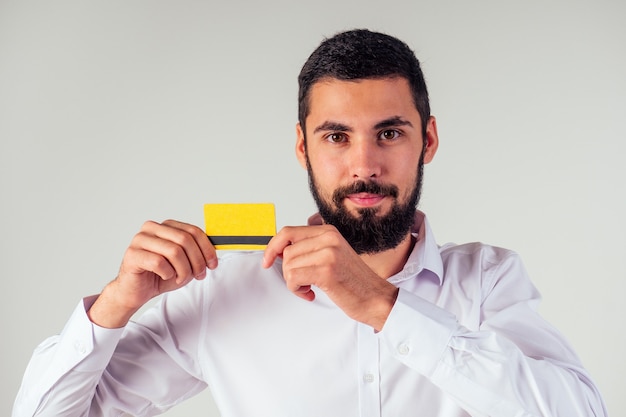 Hombre de negocios con una camisa blanca con tarjeta de crédito yellpw. Mirando a la cámara, sonriendo. venta de viernes negro y gastar dinero concepto