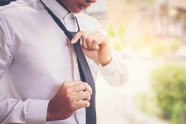 hombre de negocios en camisa vestirse y ajustar corbata en el cuello