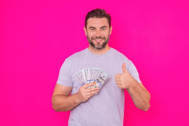 Hombre de negocios en camiseta con dinero en efectivo dólares billetes aislados sobre fondo de estudio rosa cien