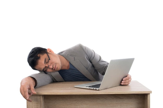 Un hombre de negocios cansado apoyado en la mesa mientras sostiene una computadora portátil contra un fondo blanco