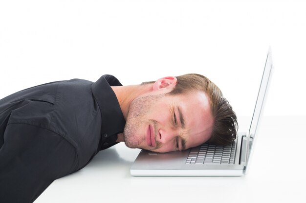 Hombre de negocios cansado descansando en la computadora portátil