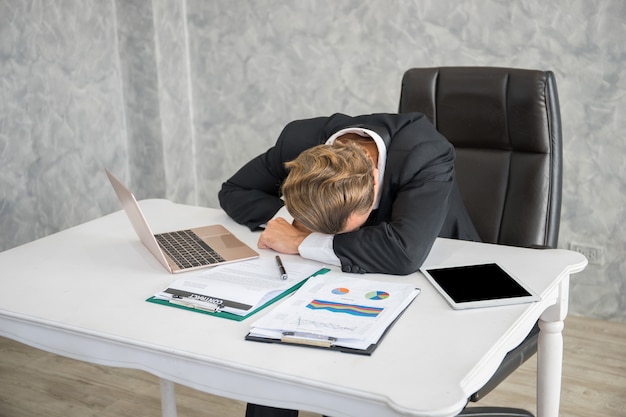 Hombre de negocios cansado durmiendo en el lugar de trabajo después del trabajo duro y el trabajo todo el día.