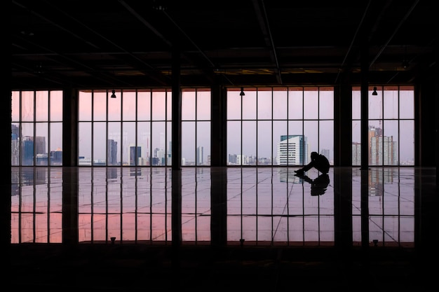 Foto hombre de negocios cansado o deprimido sentado en el suelo y tomados de la mano en la cabeza solo dentro de la habitación vacía del edificio de oficinas.