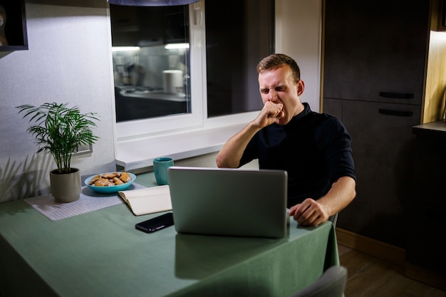 Hombre de negocios cansado sentado a la mesa en casa, casa moderna y acogedora, mirando la pantalla del portátil, se siente satisfecho con el orgullo por el trabajo realizado, la persona tranquila está descansando, con las manos apoyadas detrás de la cabeza