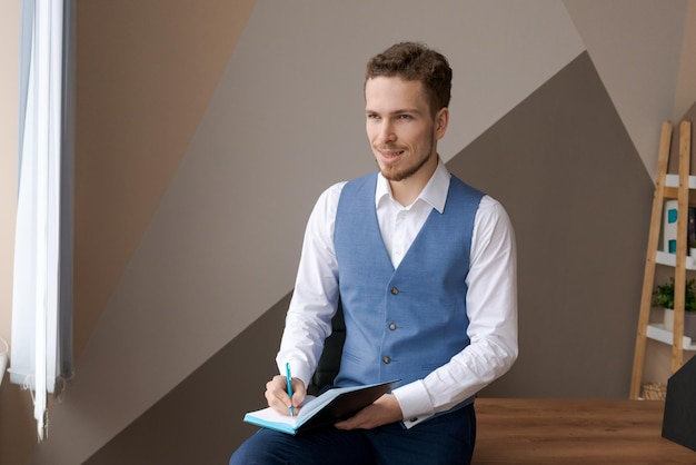 Hombre de negocios casual con bolígrafo por escrito en un cuaderno de papel en la oficina con camisa