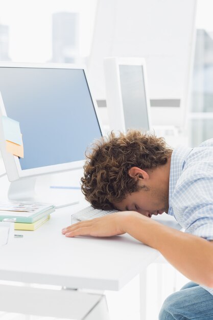 Hombre de negocios casual con la cabeza sobre el teclado en el escritorio