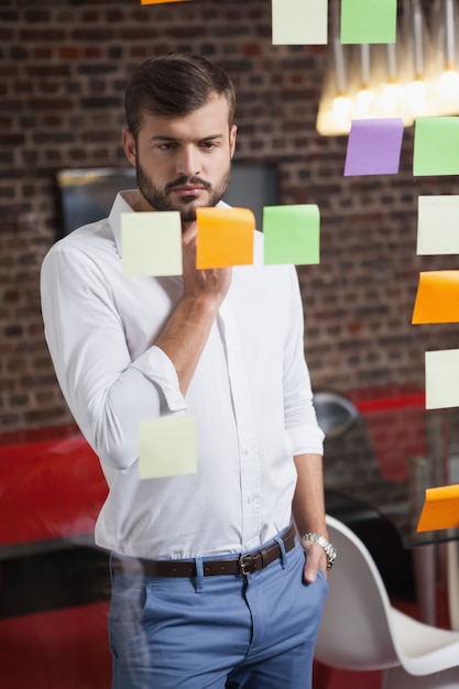 Hombre de negocios casual mirando notas adhesivas