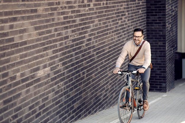 Un hombre de negocios casual montando una bicicleta en la calle cuesta arriba