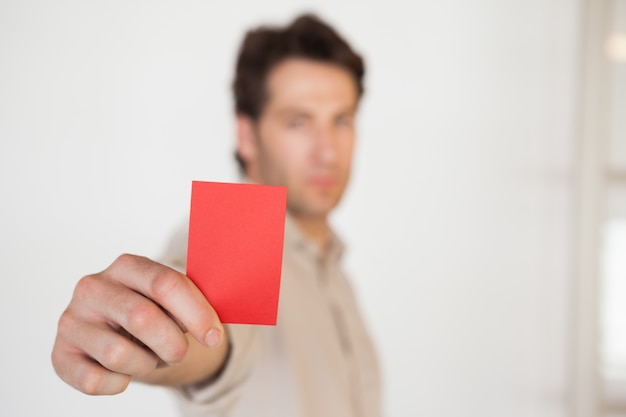 Hombre de negocios casual mostrando tarjeta roja