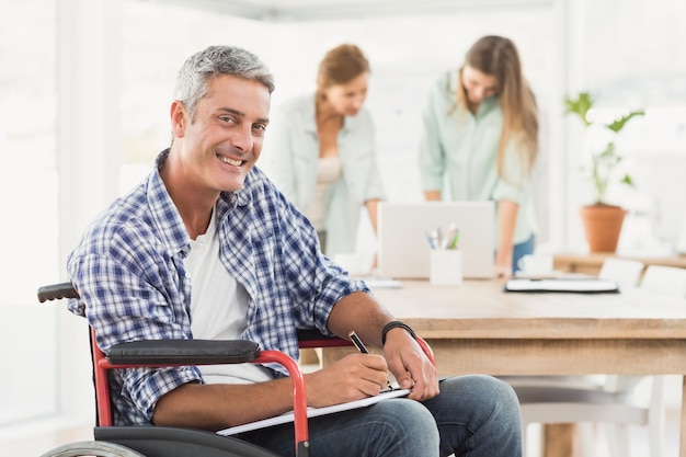 Hombre de negocios casual en silla de ruedas con bloc de notas