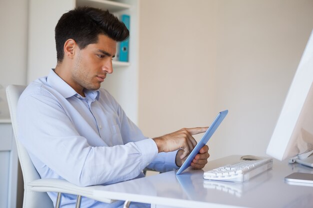 Hombre de negocios casual trabajando en su tableta en su escritorio