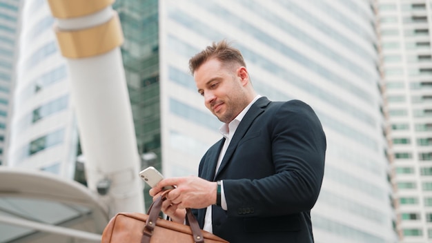 Hombre de negocios caucásico comprobando el teléfono móvil mientras está de pie en urbano urbano