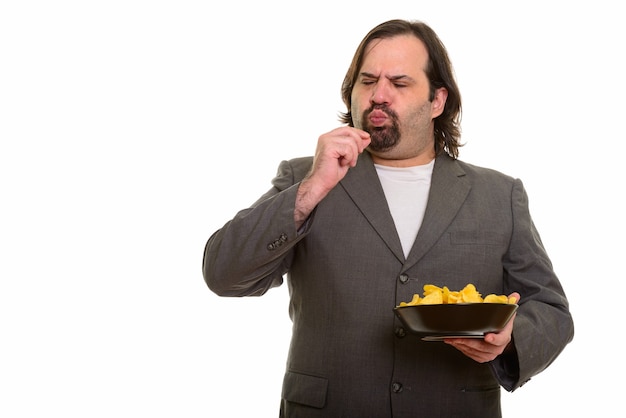 Hombre de negocios caucásico gordo comiendo deliciosamente tazón de patatas fritas aislado en blanco