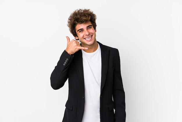 Hombre de negocios caucásico joven contra una pared blanca aislada mostrando un gesto de llamada de teléfono móvil con los dedos.