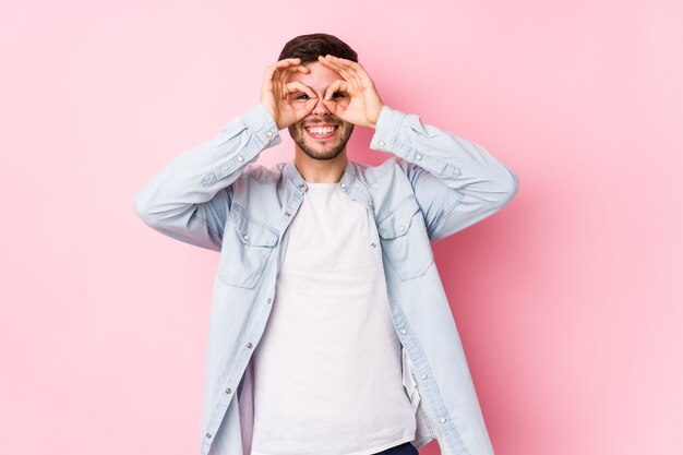 Hombre de negocios caucásico joven que presenta en una superficie blanca aislada que muestra bien firme sobre los ojos <mixto>