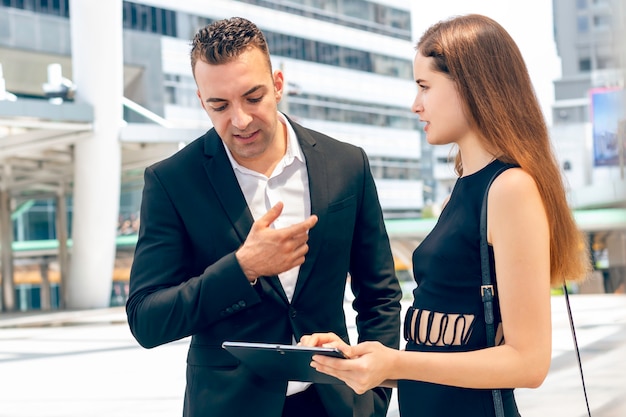 Hombre de negocios caucásico profesional discutiendo ideas con tableta en reunión mujer de negocios fuera.