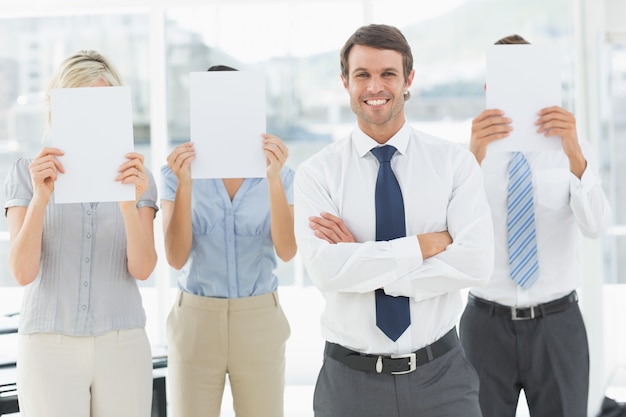 Hombre de negocios con colegas con papel en blanco frente a caras