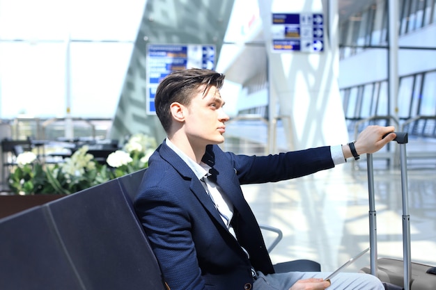 Hombre de negocios comprobando el tiempo y usando la tableta en el aeropuerto.