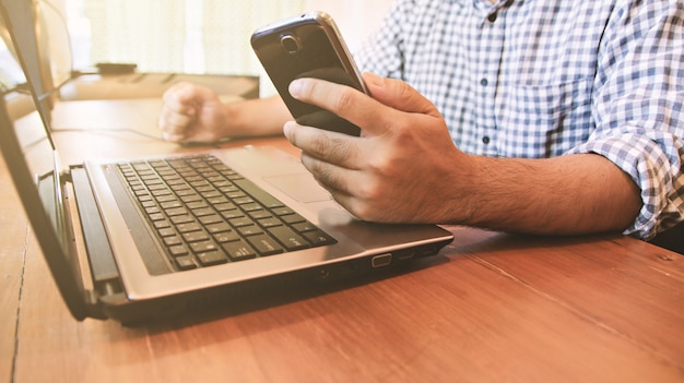 Hombre de negocios con computadora y teléfono inteligente.