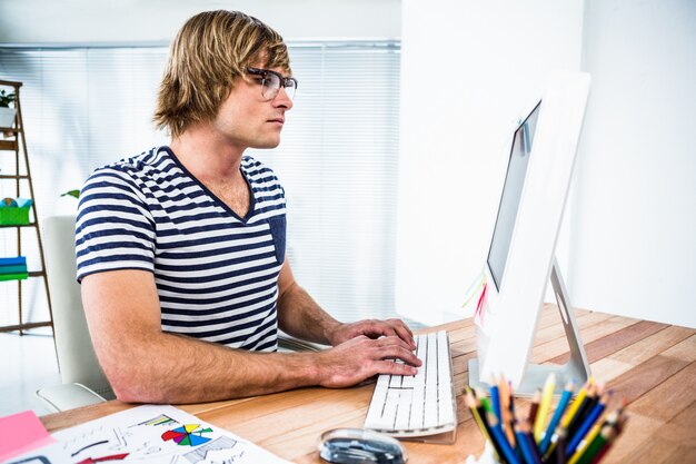 Hombre de negocios concentrado del inconformista que usa su computadora en su oficina