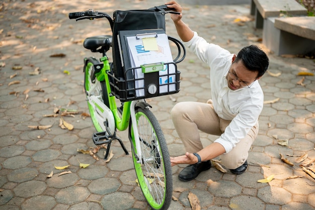 Foto un hombre de negocios concentrado inspecciona su neumático de bicicleta en un parque que se encuentra con un problema durante su viaje