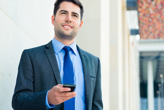 Hombre de negocios confiado al aire libre usando el teléfono