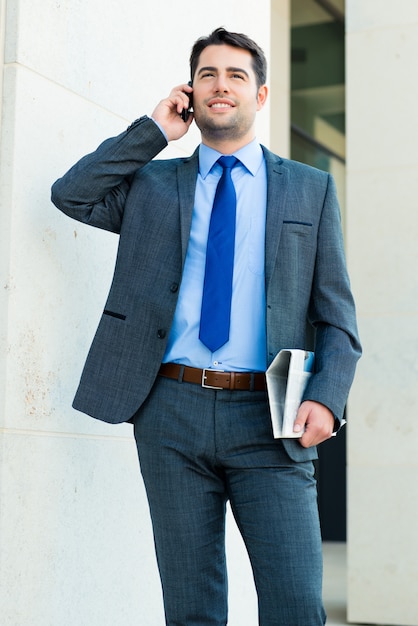 Hombre de negocios confiado al aire libre usando el teléfono